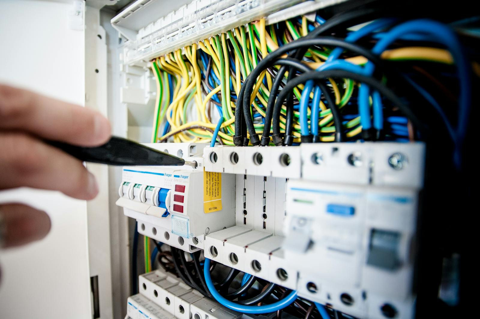 Photo by Pixabay Hand of electrician working on a circuit breaker panel with colorful wires, ensuring safe electrical connections.